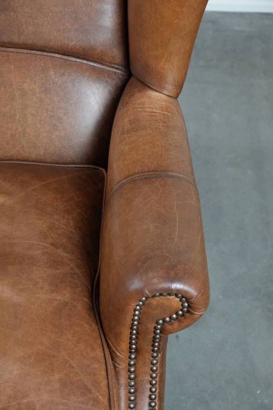 Image 1 of Tijdloze cognac kleurige oorfauteuil in Engelse stijl gemaakt van rundleer afgewerkt met siernagels