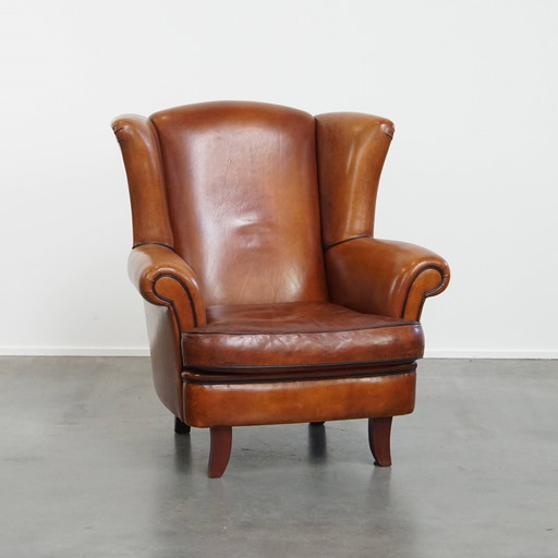 Fauteuil à oreilles en peau de mouton avec passepoil noir