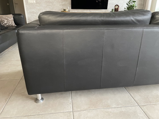 Image 1 of Black leather three-seater sofa.