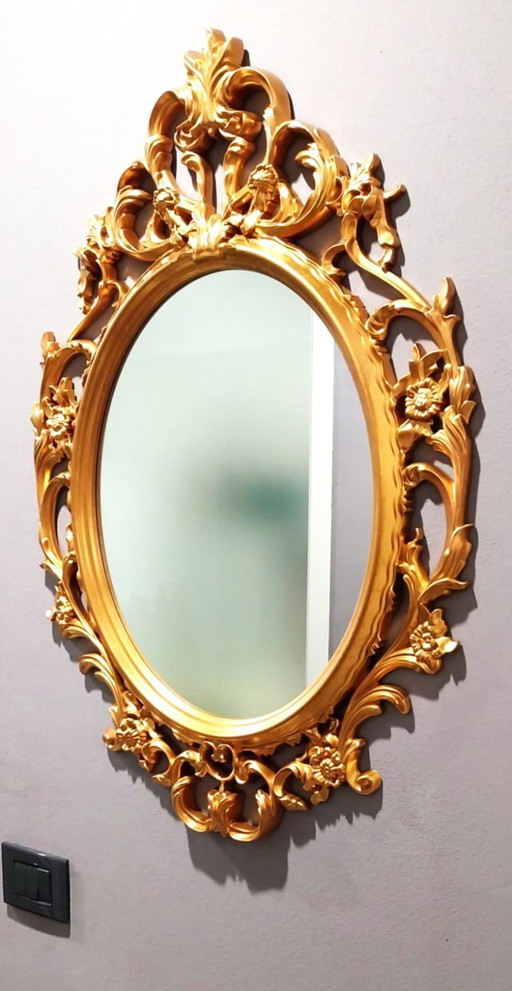 Vendo elegante espejo de pared de estilo barroco/rococó, con marco ovalado ricamente decorado y acabado dorado.