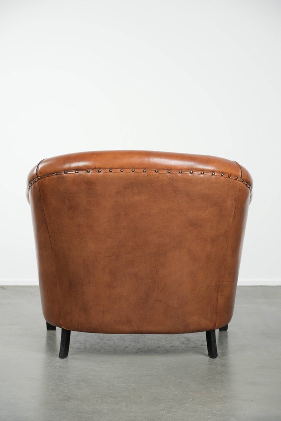 Image 1 of Amplio sillón club de estilo inglés, tapizado en piel de oveja, con acabado de clavos decorativos y ribetes negros.