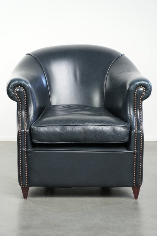 Bellissima e confortevole poltrona club in pelle bovina blu scuro dal design unico e senza tempo.