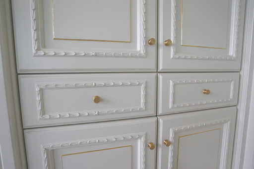 Wall cabinet with display cases, open sections, doors, gold details, fireplace, hearth, recessed lighting, etc.