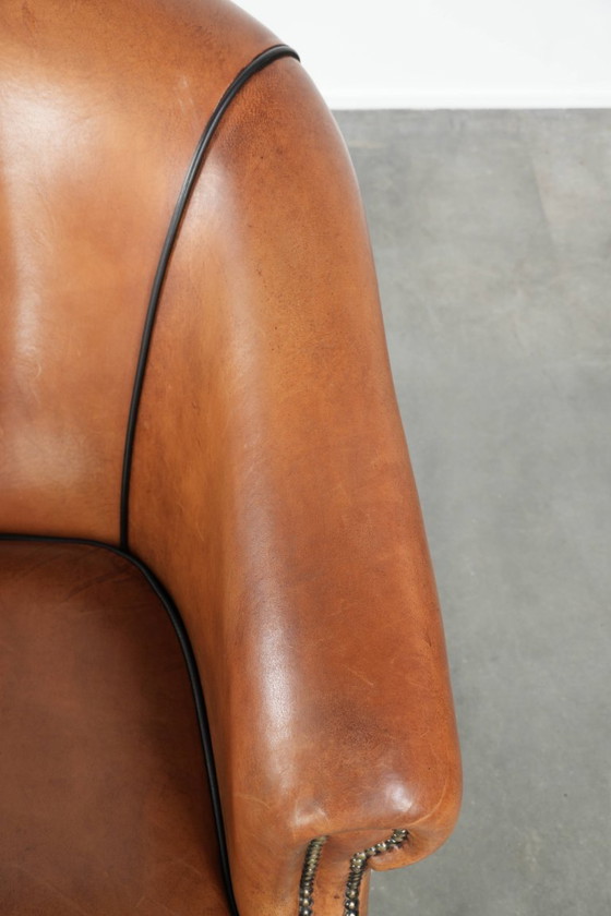 Image 1 of Amplio sillón club de estilo inglés, tapizado en piel de oveja, con acabado de clavos decorativos y ribetes negros.