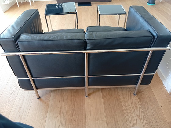 Image 1 of Een set van twee zwarte leren fauteuils en een bank.