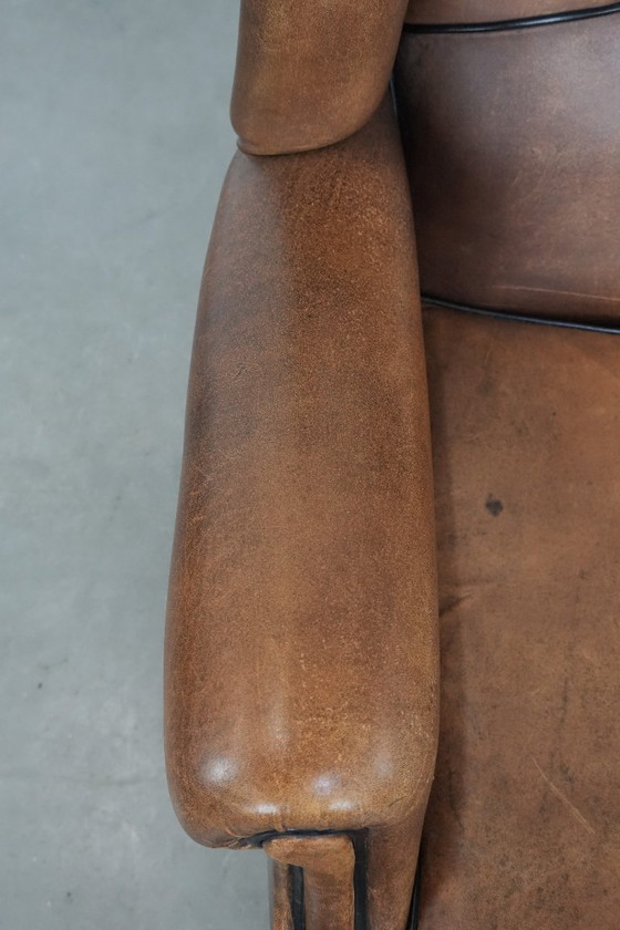 Image 1 of Poltrona a orecchioni in pelle di pecora con profili neri, in buone condizioni.