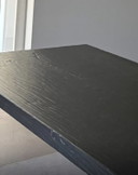 Robusto tavolo da pranzo con piano spesso 12 cm e base verniciata a polvere nera.
