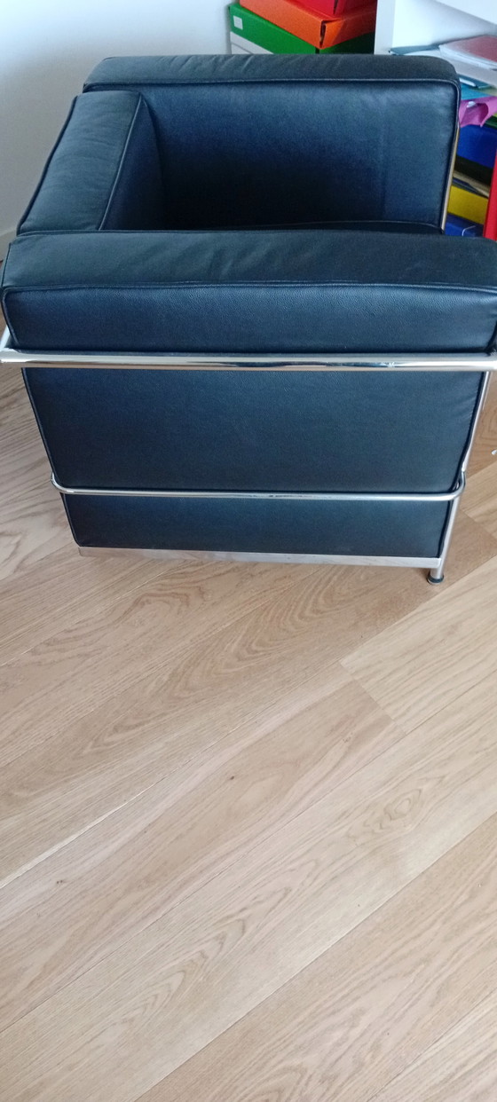 Image 1 of Een set van twee zwarte leren fauteuils en een bank.