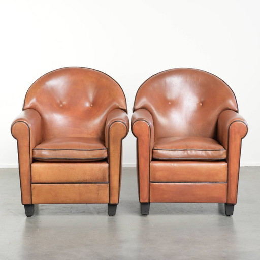 2 poltrone di design Bart van Bekhoven in pelle di pecora con schienale arrotondato e profili neri.