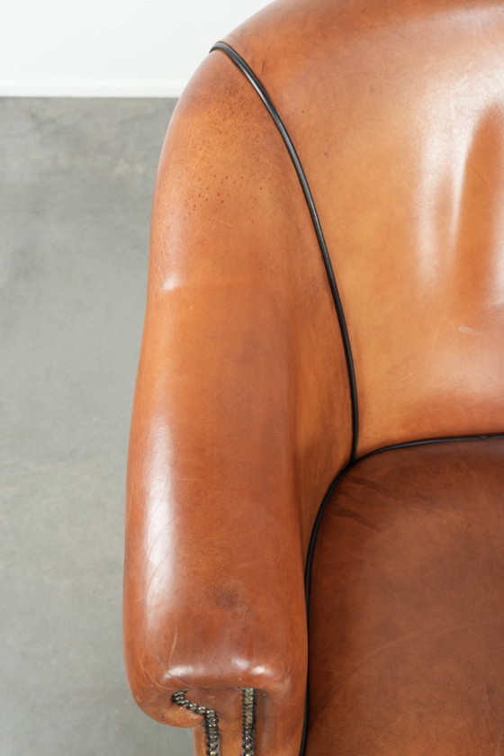 Image 1 of Amplio sillón club de estilo inglés, tapizado en piel de oveja, con acabado de clavos decorativos y ribetes negros.