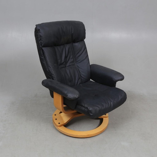 Sweden-origin Scandinavian lounge armchair with a matching ottoman, featuring a black leather and wood frame, in good condition 