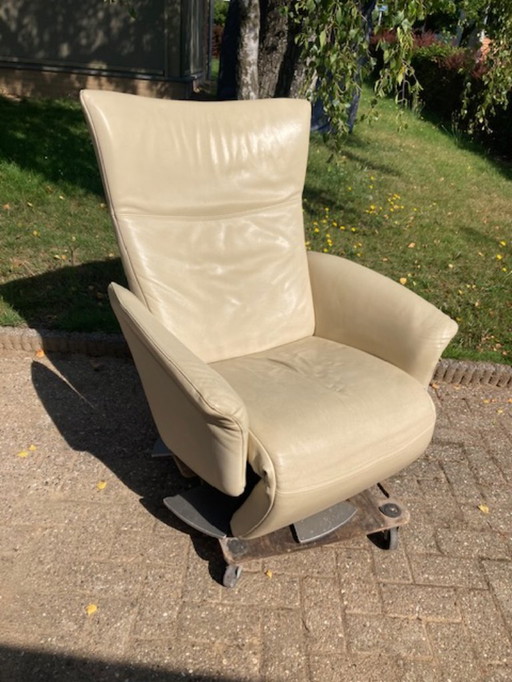 A swivel recliner armchair by Rolf Benz. Cream colored with matte chrome base. Used.