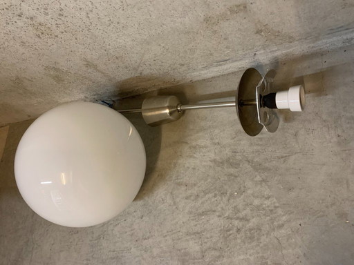 Bola blanca opalina brillante sobre péndulo de acero