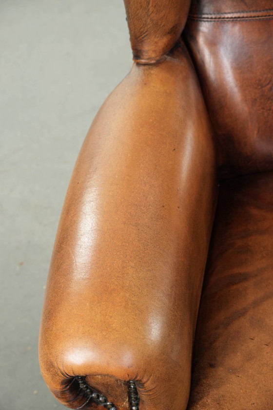 Image 1 of Comfortabele oorfauteuil gemaakt van schapenleer afgewerkt met siernagels en een karaktervolle uitstraling in Engelse stijl
