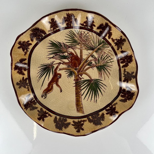 Piatto in terracotta smaltata a effetto craquelé con decorazioni esotiche raffiguranti scimmie e palme, prima metà del XX