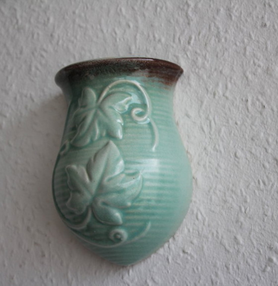 Image 1 of Lichtgroene vintage keramische wandvaas met wijnrankdecoratie.