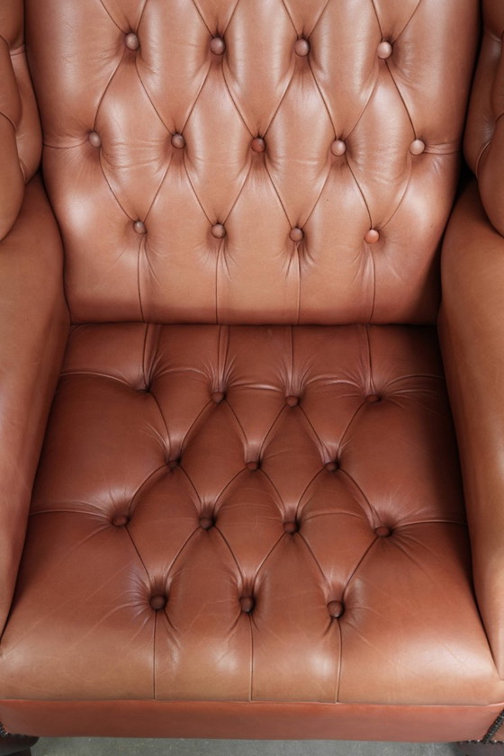 Image 1 of Fauteuil Chesterfield à oreilles en cuir de vachette anglais, assise capitonnée, avec une belle patine et de jolies couleurs.
