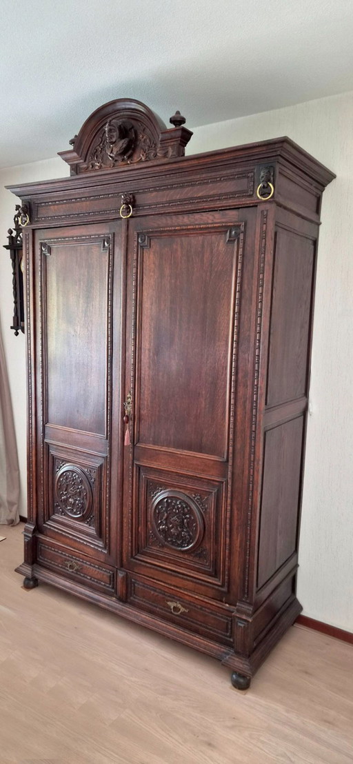 Antiker Schrank aus dunklem Holz mit detaillierten Holzschnitzereien (Till Eulenspiegel)