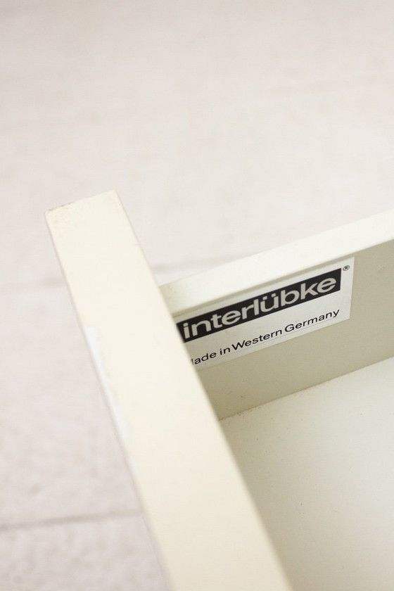 Image 1 of Mesita de noche de madera Interlübke con patas de metal lacado en blanco.