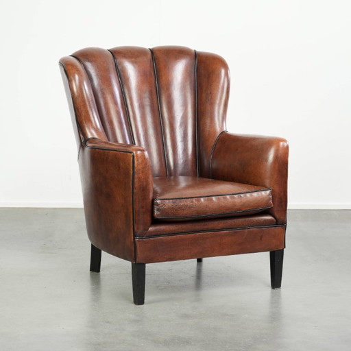 Fauteuil unique en peau de mouton aux couleurs chaudes et profondes, orné d'un passepoil noir. – Leather