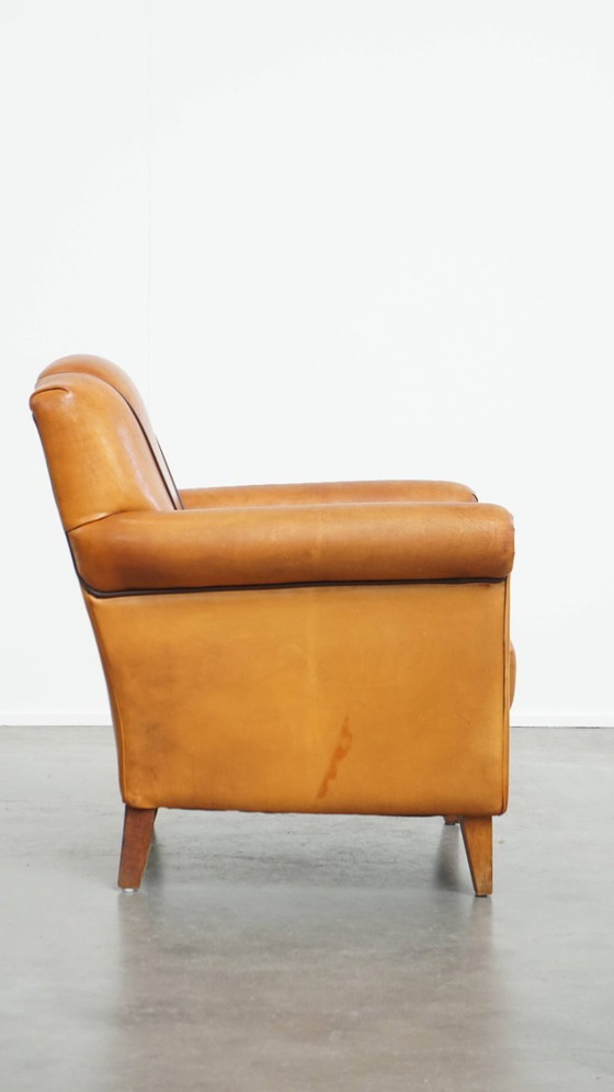Image 1 of Schapenleren armchair met een afwerking met donkerbruine biezen