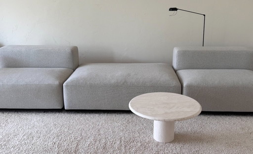 Round coffee table made of light-colored natural stone with a cylindrical base in a minimalist design.
