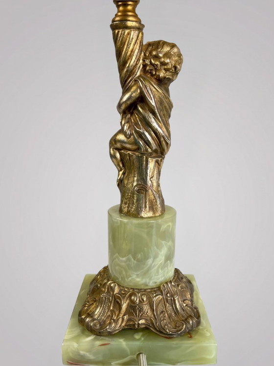 Image 1 of Lampe de table style Louis XVI au putto en métal doré et base effet onyx – 48 cm