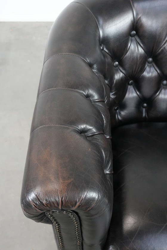 Image 1 of Donkere luxe rundleren Chesterfield clubfauteuil in Engelse stijl, afgewerkt met siernagels
