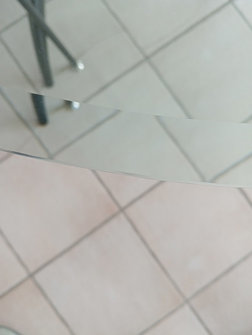 Mesa de comedor ovalada de cristal con 4 sillas negras a juego.