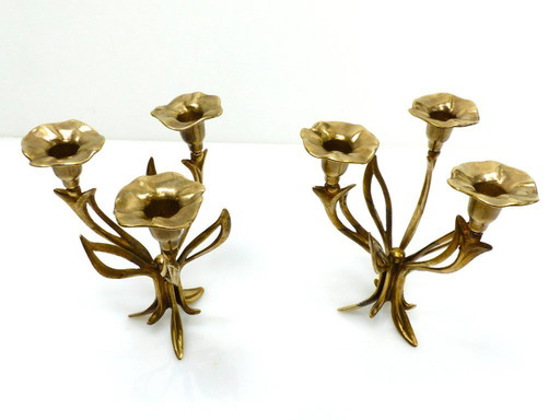 Een paar messing kandelaars met drie lichtpunten op een statief, versierd met organische bloemmotieven, circa 1960-1970.