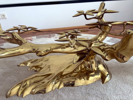 Image 1 of Sculpturale salontafel in de vorm van een boom, gemaakt van gegoten metaal, met een ovaal glazen blad.