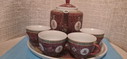 A Chinese teapot on a tray with 4 cups