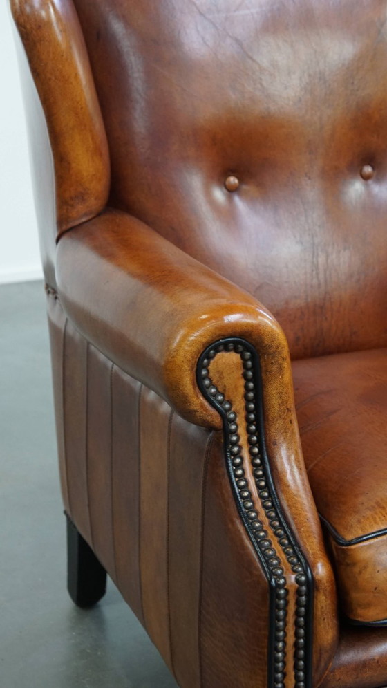 Image 1 of Comfortabele schapenleren oorfauteuil met een prachtige warme kleurstelling en een afwerking met stiksels en zwarte biezen