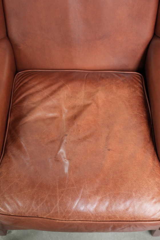 Image 1 of Comoda poltrona a orecchioni in pelle bovina color cognac in stile inglese.
