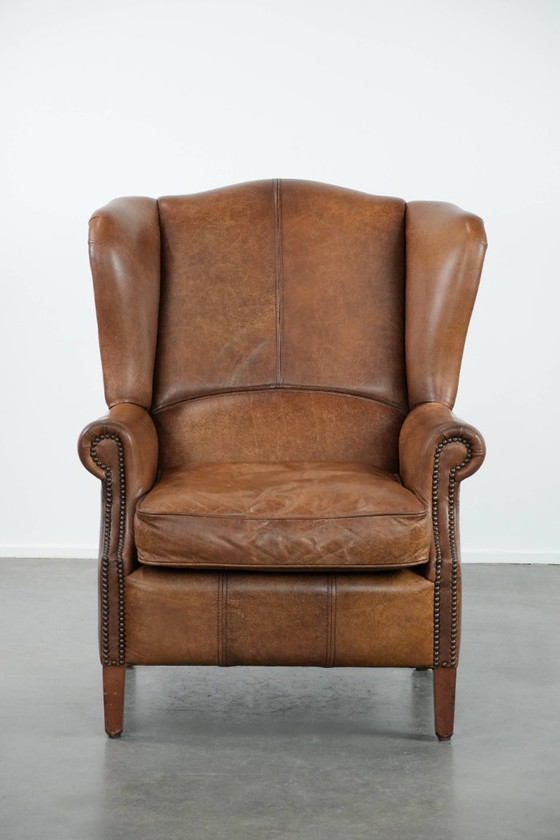 Image 1 of Tijdloze cognac kleurige oorfauteuil in Engelse stijl gemaakt van rundleer afgewerkt met siernagels