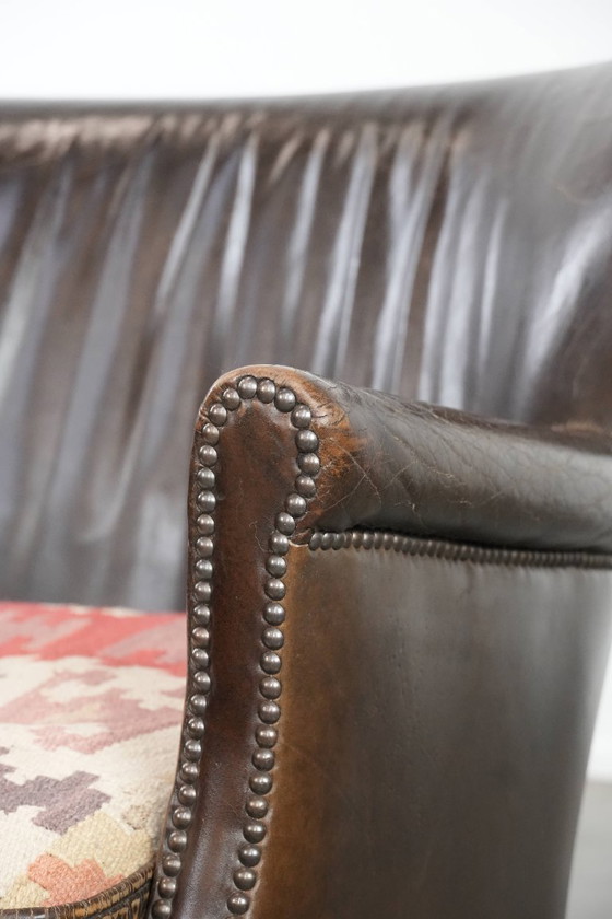 Image 1 of Subtiele donkerbruine fauteuil gemaakt van rundleer met een omkeerbaar Kelim zitkussen