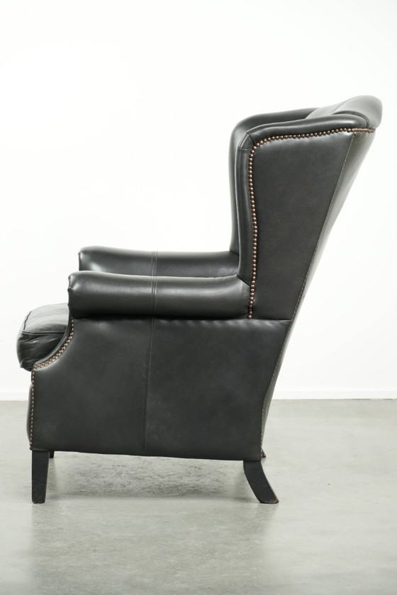 Image 1 of Zwarte rundleren oorfauteuil in een klassiek Engelse stijl