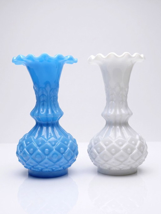 Een paar kleine vintage vaasjes van wit en blauw opaalglas, versierd met ananassen. – vazen