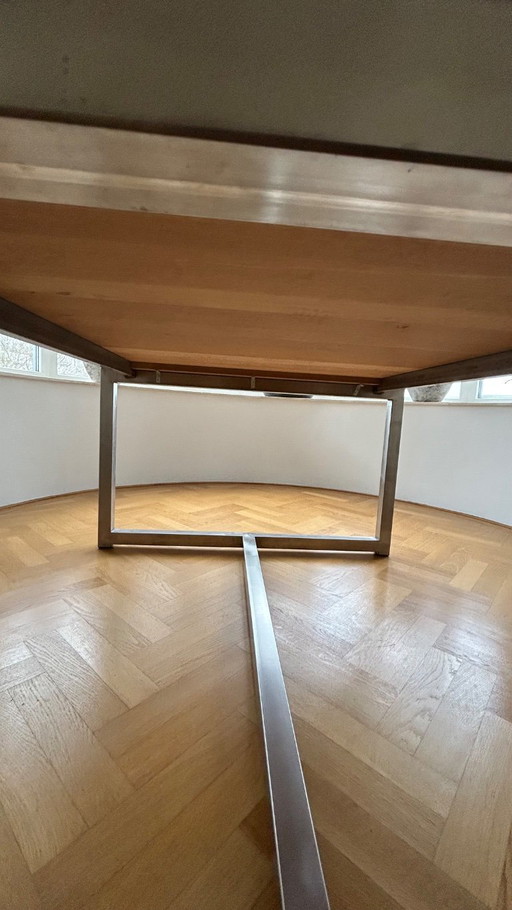 Mesa de comedor de diseño con estructura de acero inoxidable y marco de roble blanqueado.