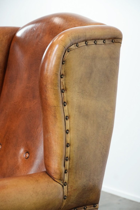 Image 1 of Grote schapenleren oorfauteuil met zwarte biezen en siernagels