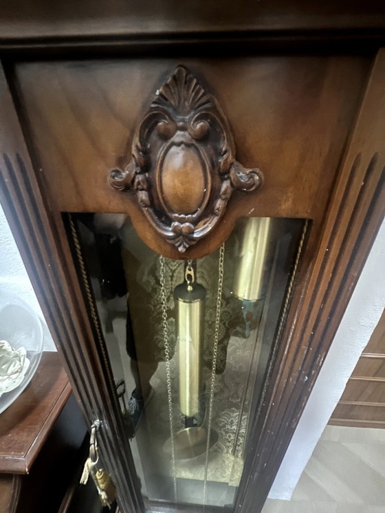 Image 1 of Eine hölzerne Pendeluhr mit einem Schweizer mechanischen Uhrwerk