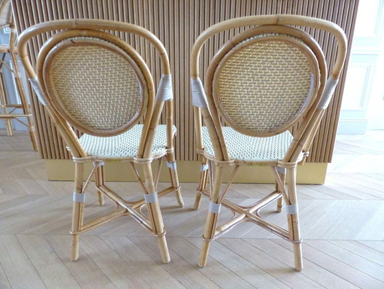 Image 1 of Een paar Parijse bistrostolen van Maison Louis Drucker in licht Manila-rotan.