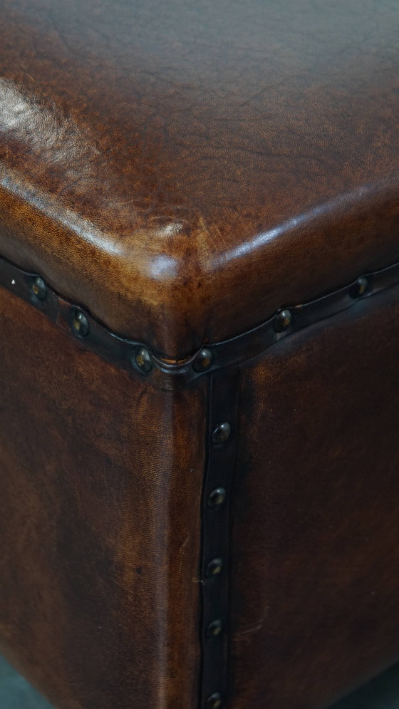 Image 1 of Cognac-kleurige schapenleren hocker met siernagels
