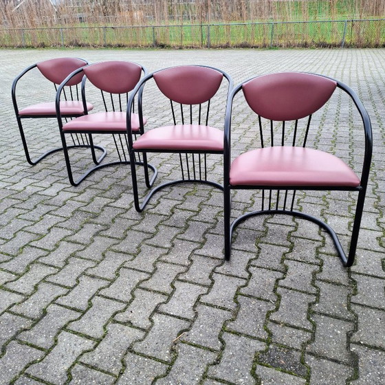 Image 1 of This is a set of four vintage 'Memphis' style chairs with a black metal frame and burgundy upholstery.