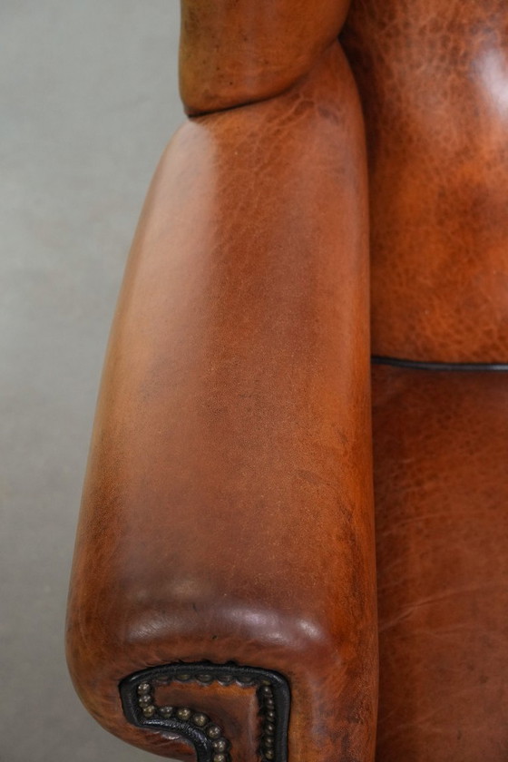 Image 1 of Grote oorfauteuil gemaakt van schapenleer met zwarte biezen en siernagels