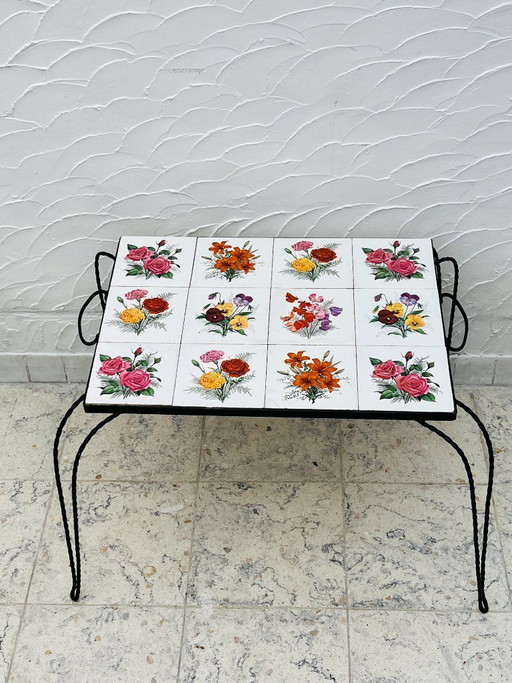 Vintage salontafel van smeedijzer met bloemmotief op de tegels.