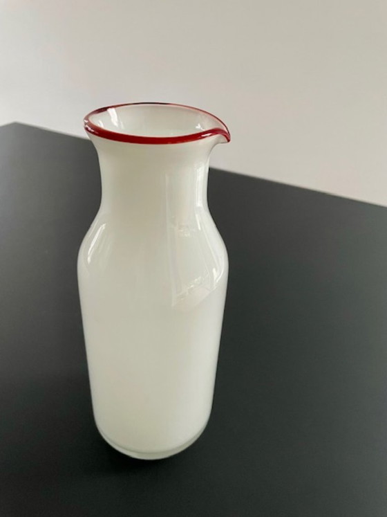 Image 1 of Caraffa dal design scandinavo in vetro bianco con bordo rosso.