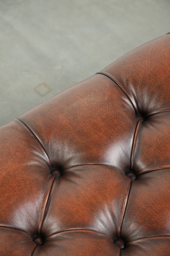 Image 1 of Grote bruine rundleren chesterfield hocker in Engelse stijl met sierlijke poten en messing wieltjes