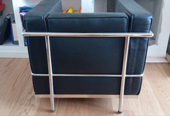 Image 1 of Een set van twee zwarte leren fauteuils en een bank.