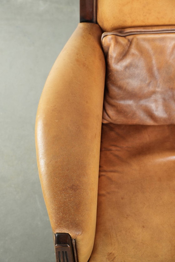 Image 1 of Cómodo sillón de diseño Art Déco en color coñac, fabricado en piel de oveja combinada con madera y con respaldo alto.